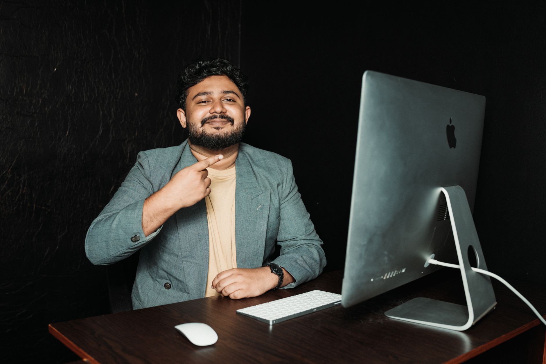 Un homme dans un bureau moderne, souriant devant un ordinateur, dans un environnement professionnel.